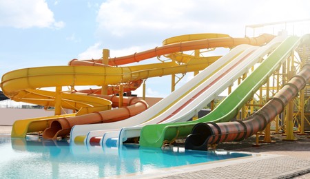 Image of Beautiful view of water park with colorful slides and swimming pool on sunny day 