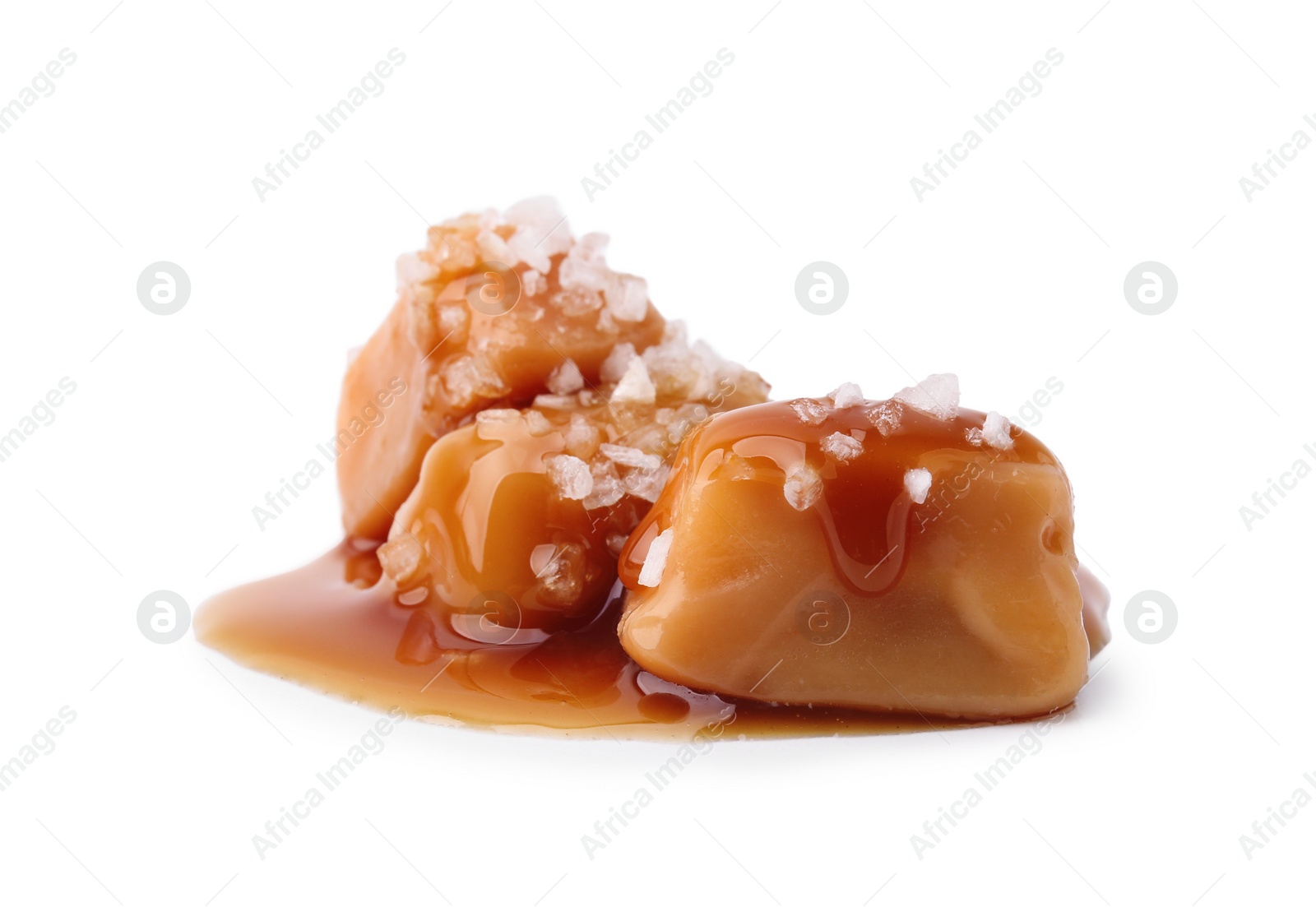 Photo of Yummy caramel candies and sea salt isolated on white