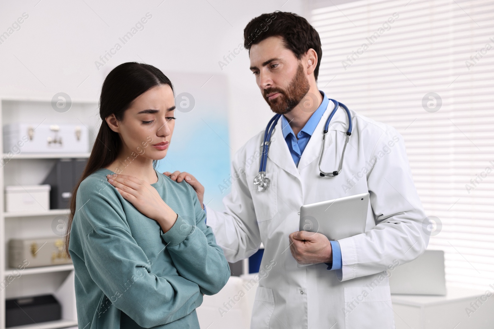 Photo of Doctor with tablet consulting patient during appointment in clinic