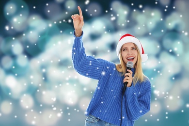Image of Happy woman in Santa hat singing on bright background, bokeh effect