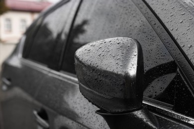 Photo of Car with side view mirror in drops of water outdoors, closeup
