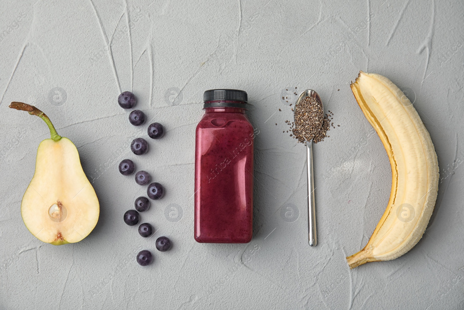 Photo of Flat lay composition with ingredients for delicious acai cocktail and bottle of juice on gray table