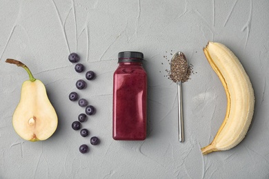 Photo of Flat lay composition with ingredients for delicious acai cocktail and bottle of juice on gray table