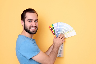 Young man with color palette on yellow background