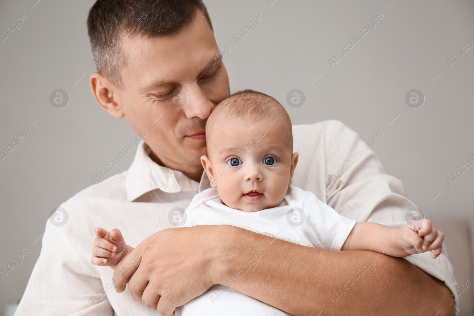 Photo of Happy father holding his cute baby on grey background