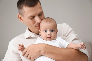 Photo of Happy father holding his cute baby on grey background