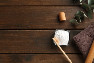 Tooth powder, brush, towel and eucalyptus on wooden table, flat lay. Space for text