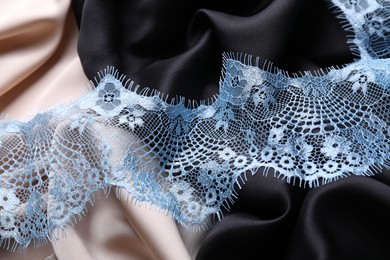 Photo of Beautiful light blue lace on color fabrics, closeup