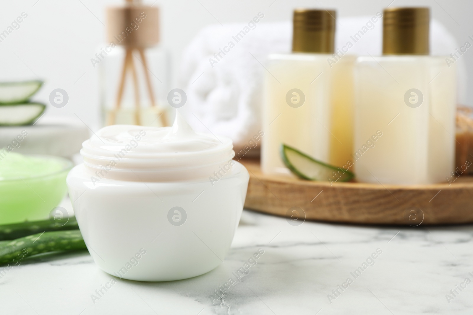 Photo of Open jar of aloe cream on white marble table. Organic cosmetics