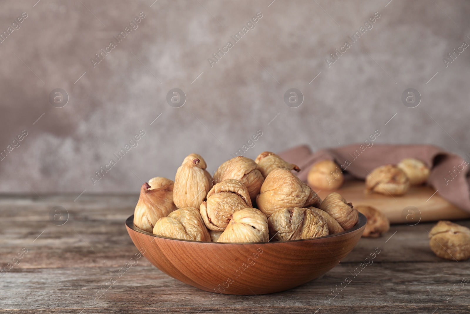 Photo of Wooden bowl with dried figs on table, space for text. Healthy fruit