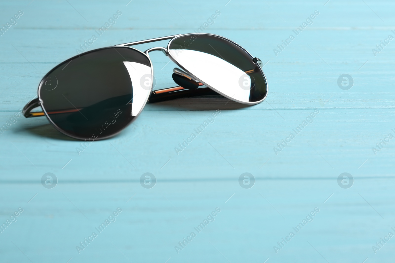 Photo of Stylish sunglasses on blue wooden background. Fashionable accessory