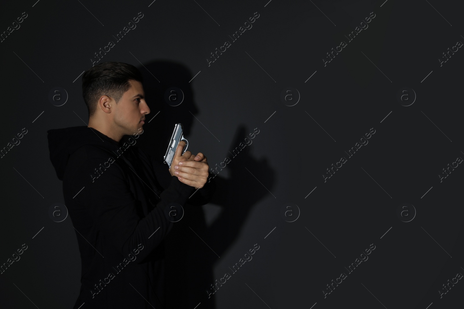 Photo of Professional killer with gun on black background. Space for text