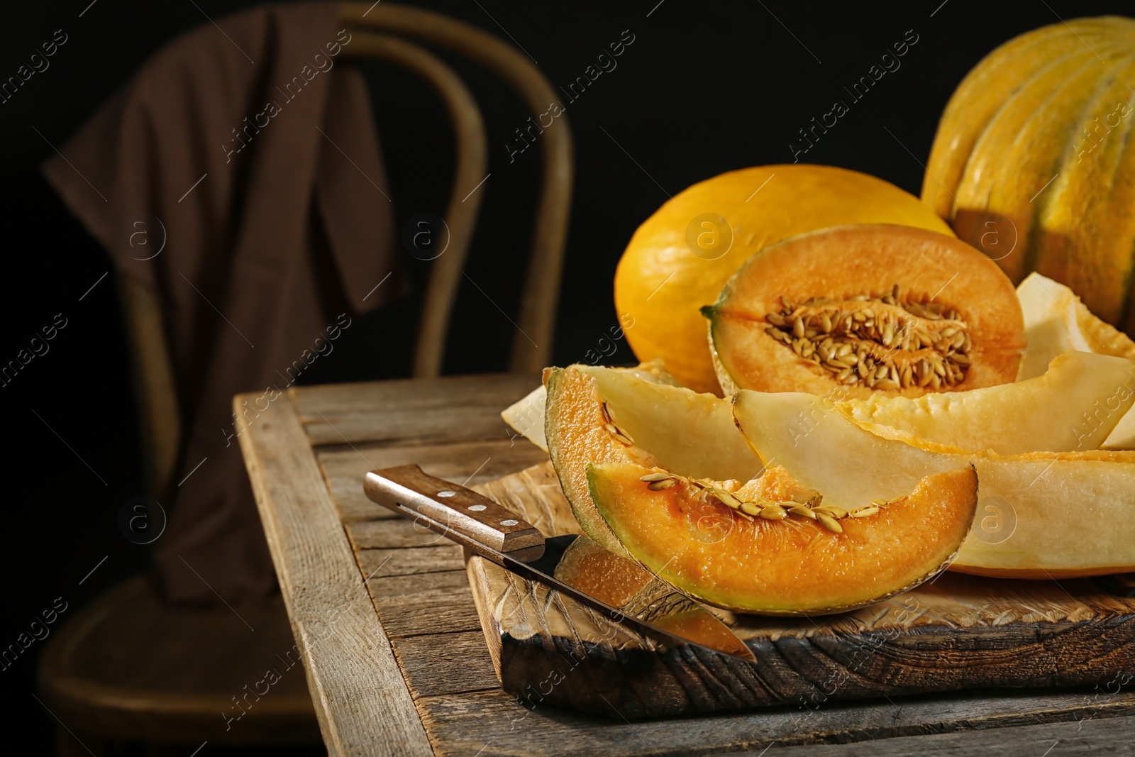 Photo of Slices of assorted melons on table against black background