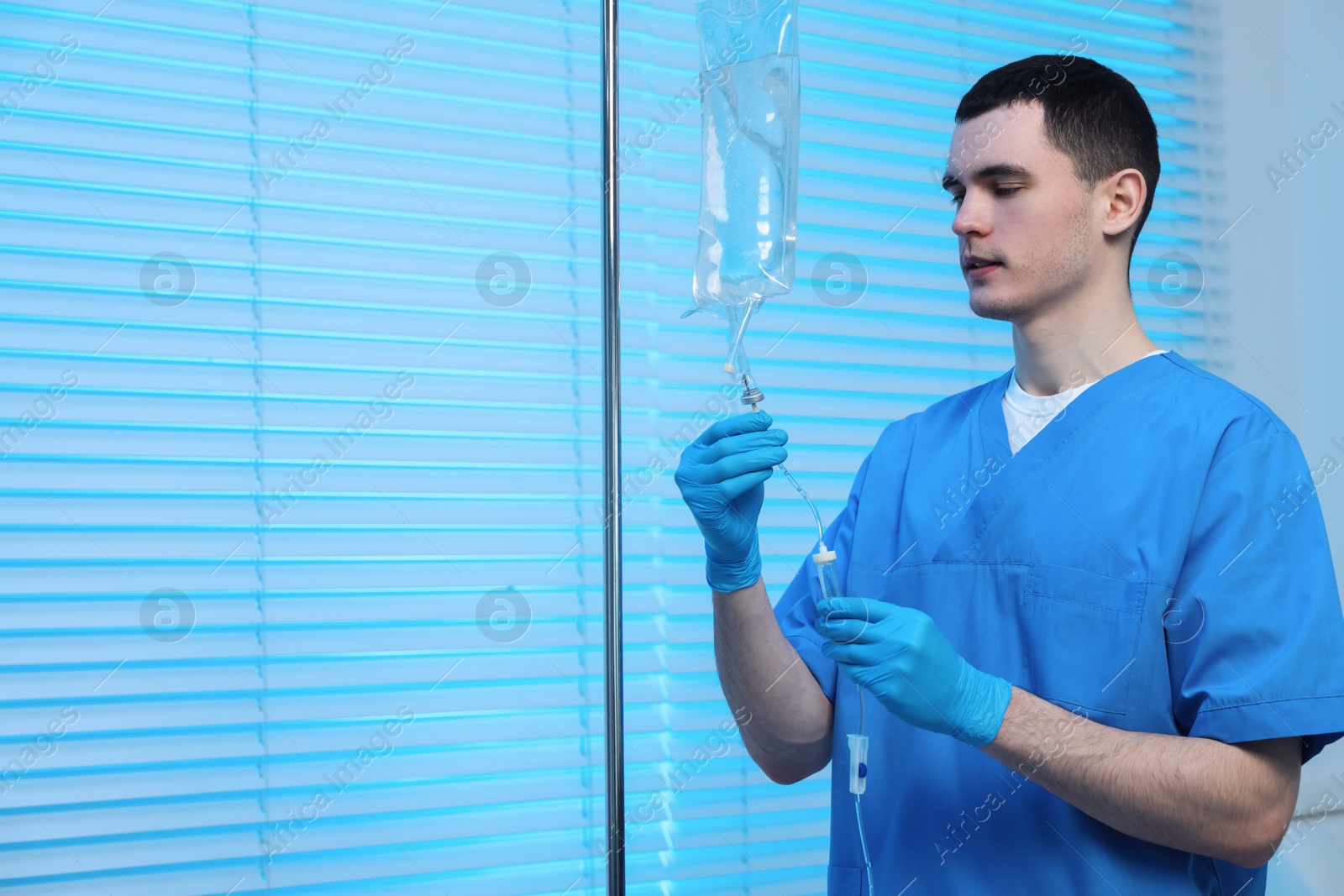 Photo of Nurse setting up IV drip in hospital, space for text