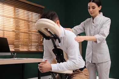 Man receiving massage in modern chair indoors