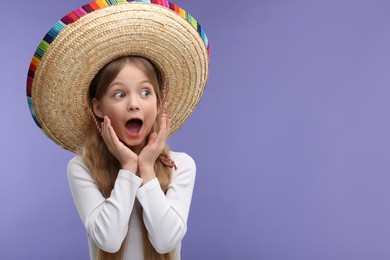 Photo of Emotional girl in Mexican sombrero hat on purple background. Space for text