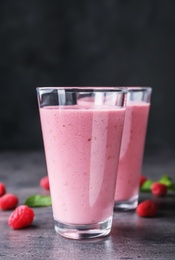 Delicious smoothie in glasses and fresh raspberries on table