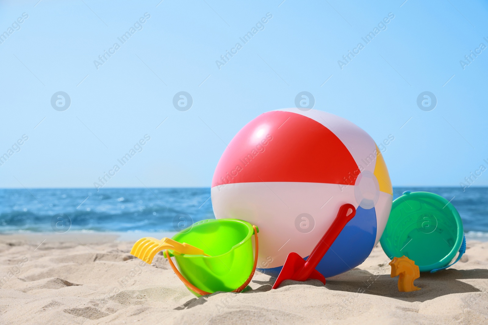 Photo of Different sand toys and beach ball near sea