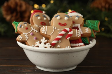 Photo of Delicious homemade Christmas cookies in bowl on wooden table against blurred festive lights
