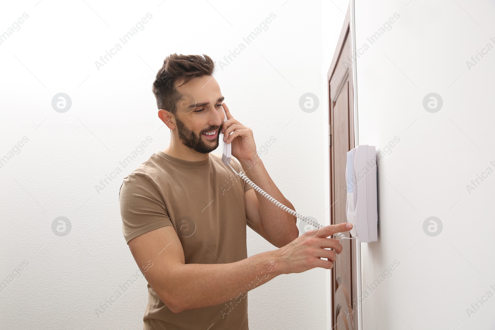 Photo of Man with handset answering intercom call indoors