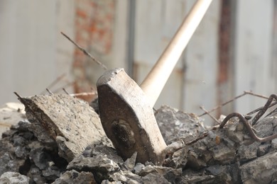 Photo of Sledgehammer on pile of broken stones outdoors, closeup