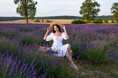 Photo of Beautiful young woman sitting in lavender field