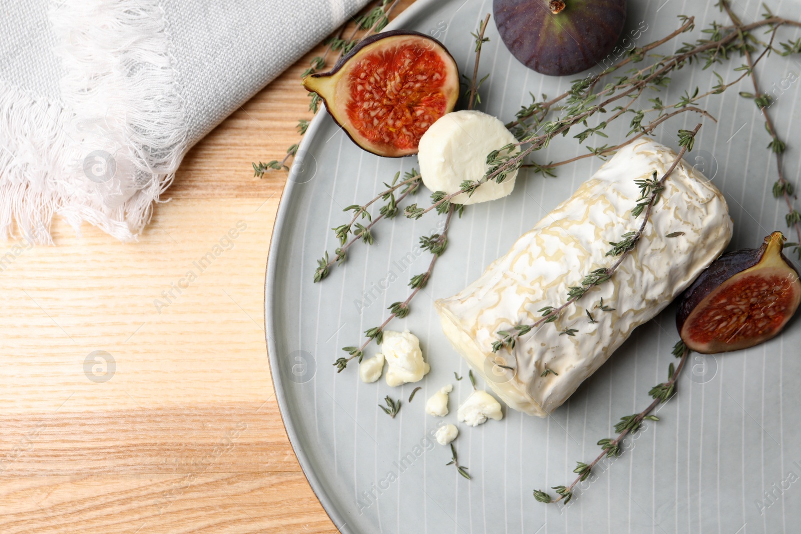 Photo of Delicious goat cheese with figs and thyme on wooden table, flat lay