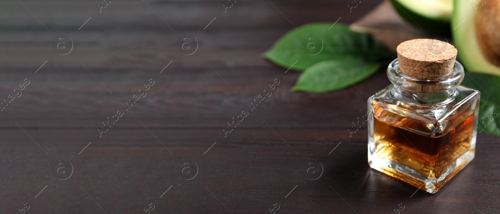 Photo of Bottle of avocado essential oil on wooden table. Space for text