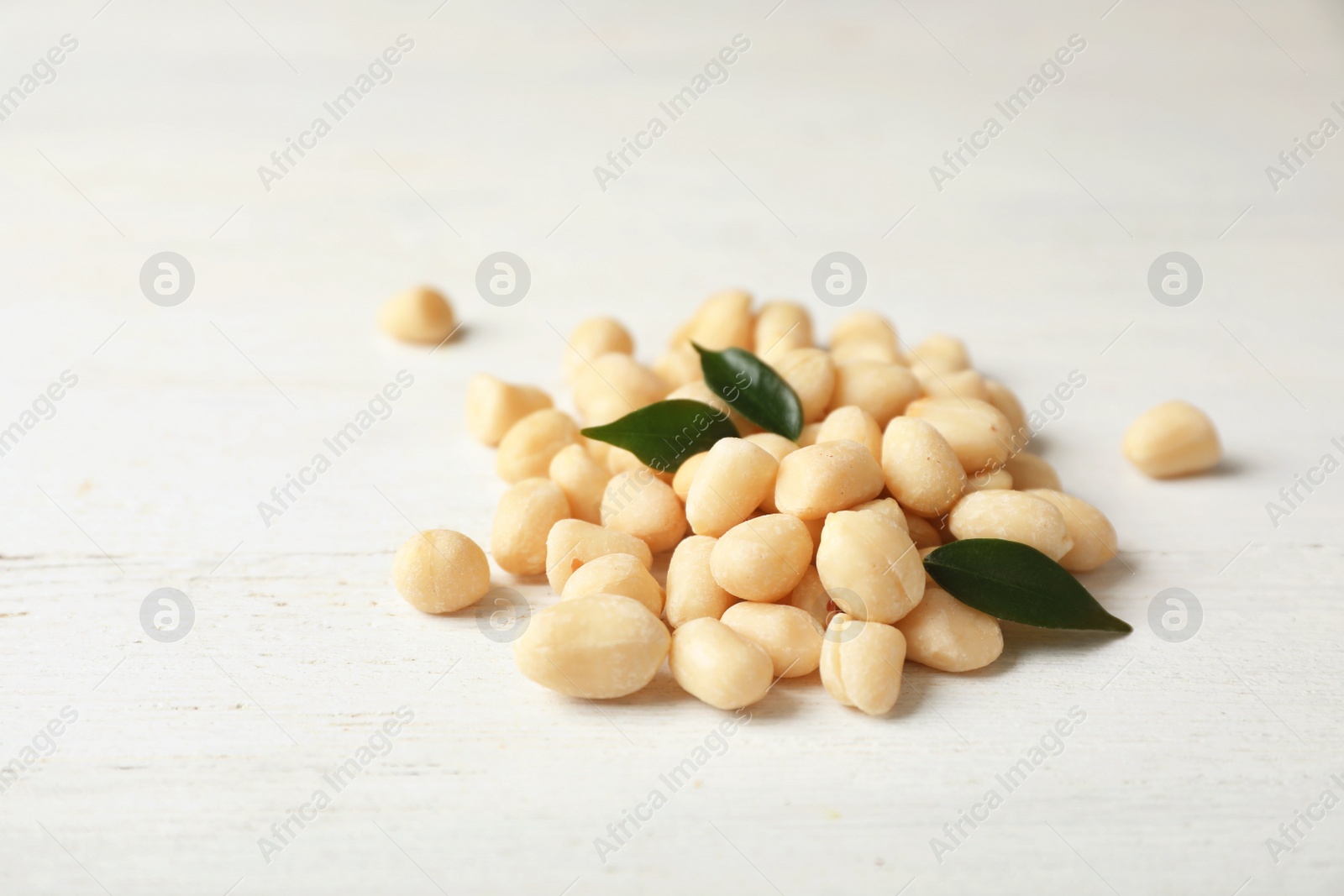 Photo of Pile of shelled peanuts and leaves on table