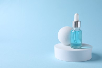 Presentation of bottle with cosmetic serum on light blue background, space for text