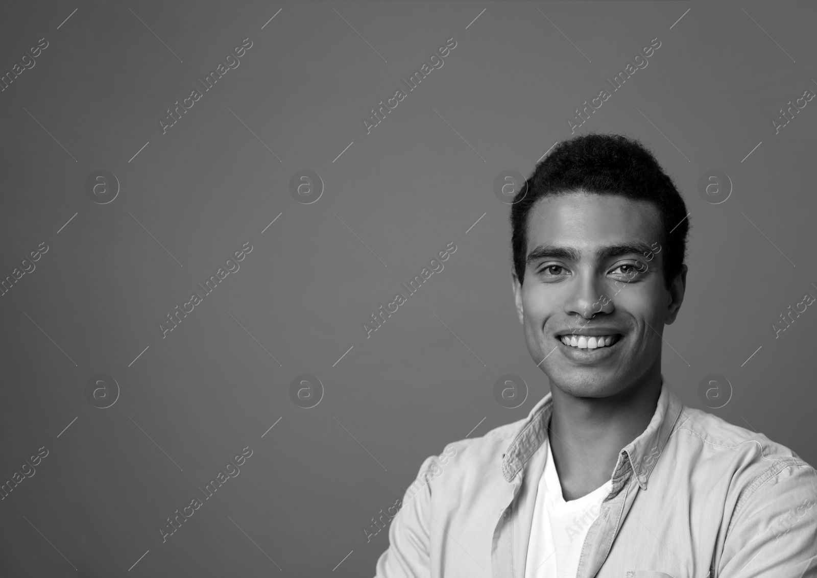 Photo of Handsome young African-American man on grey background, space for text. Black and white effect