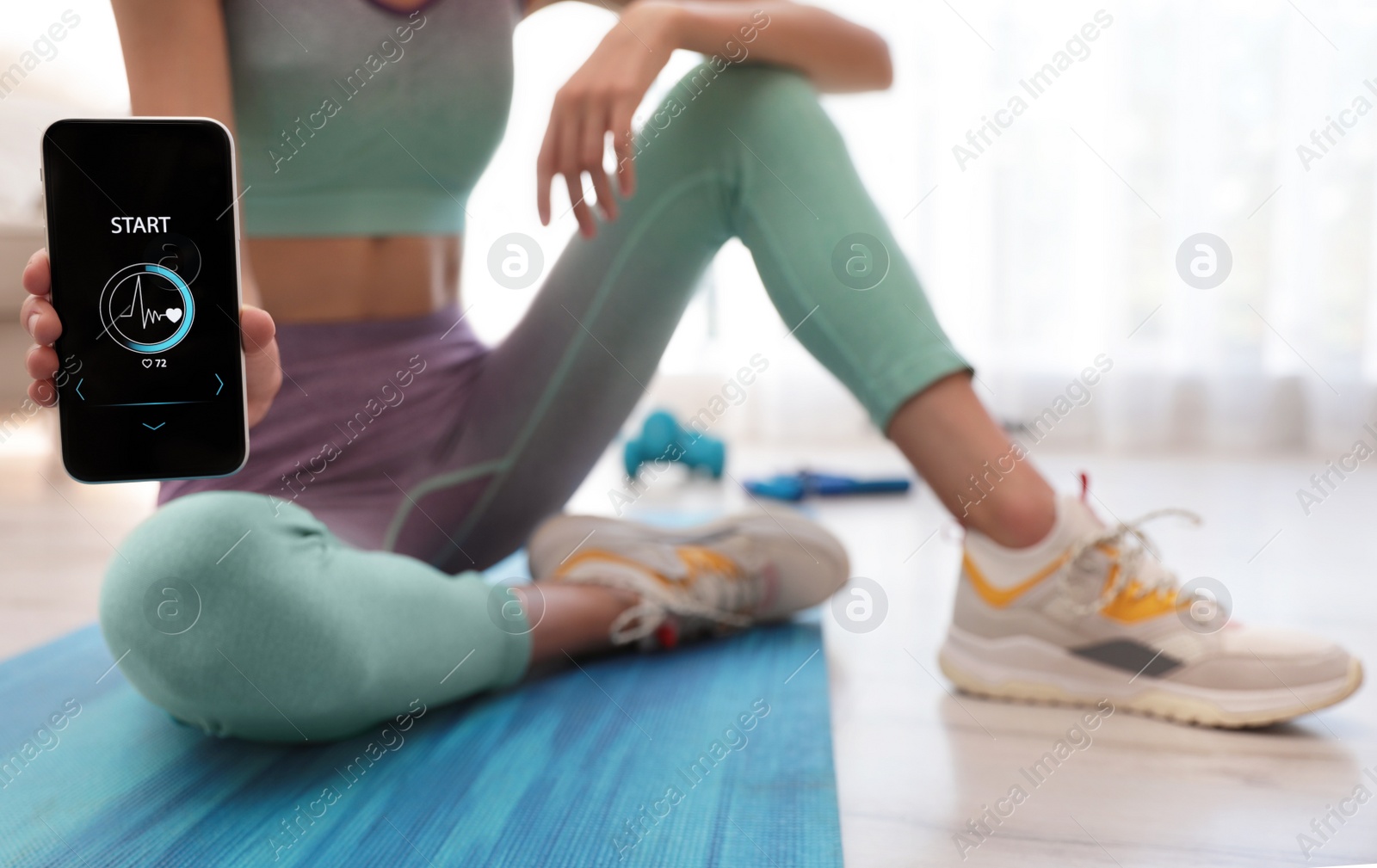 Photo of Young woman showing smartphone with fitness app at home, closeup