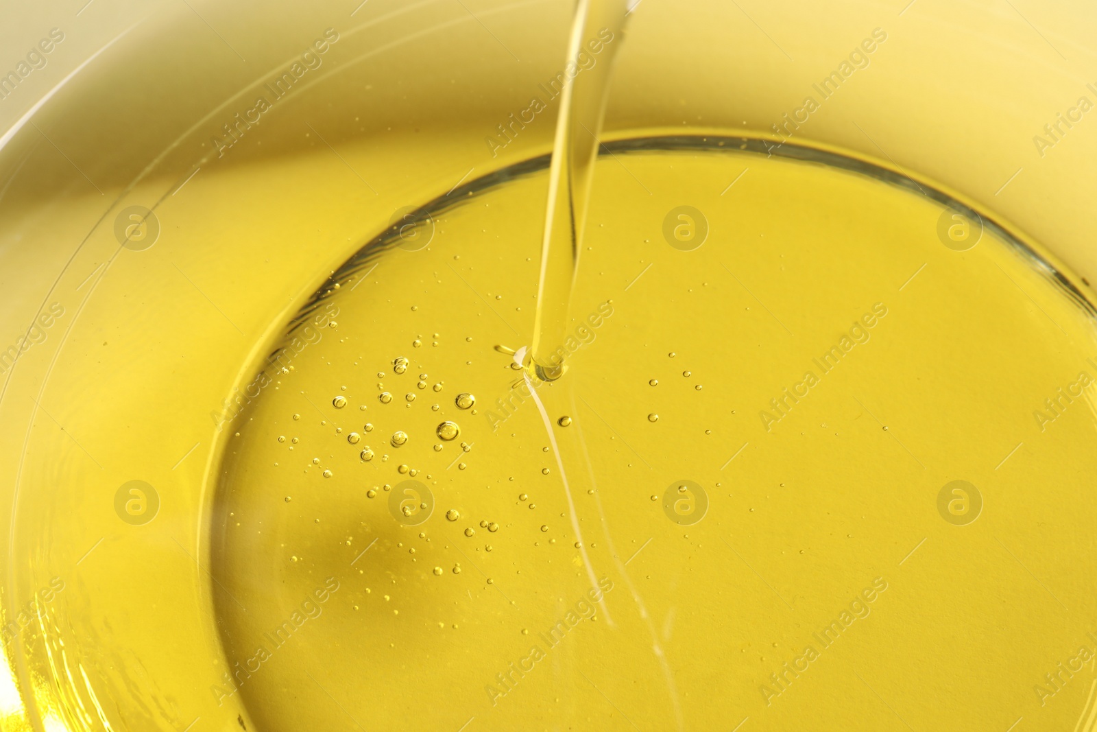 Photo of Pouring cooking oil into glass bowl, closeup