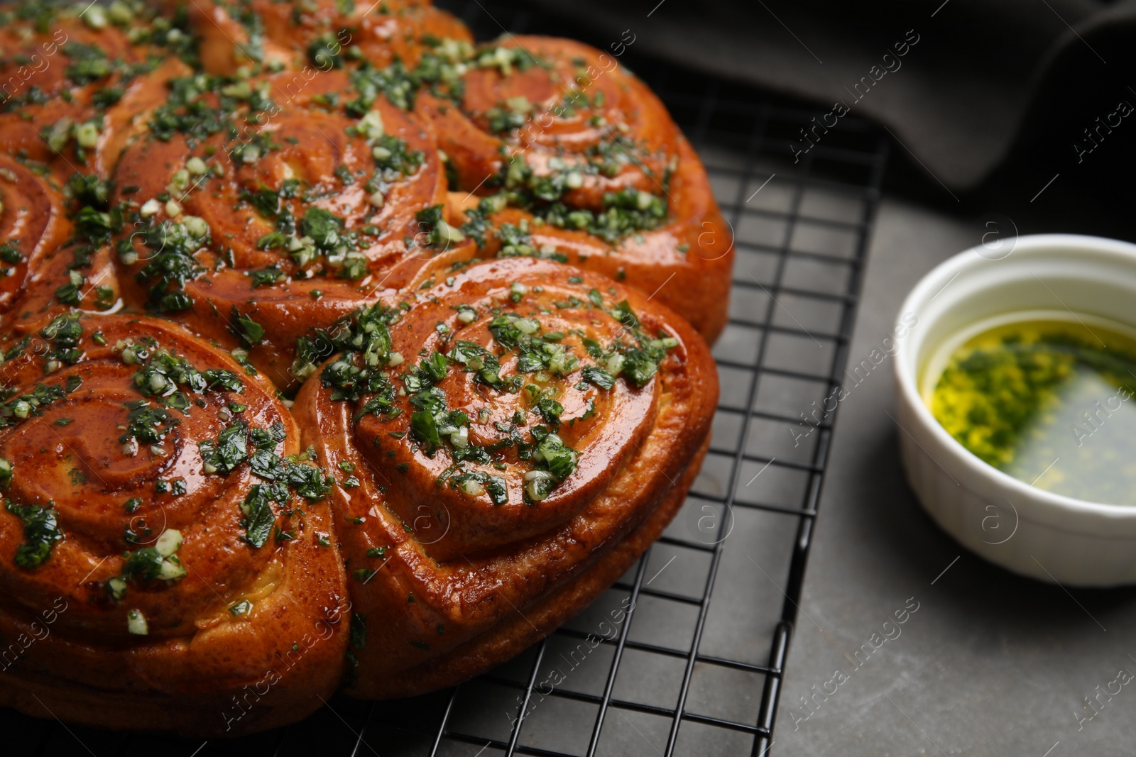 Photo of Traditional Ukrainian garlic bread with herbs (Pampushky) on grey table, closeup. Space for text