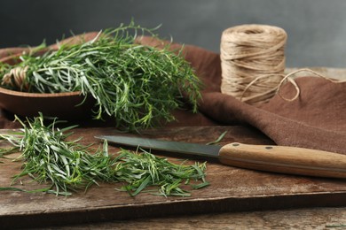 Photo of Fresh whole and cut tarragon sprigs on wooden table
