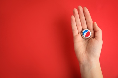 Photo of MYKOLAIV, UKRAINE - FEBRUARY 11, 2021: Woman holding Pepsi lid on red background, top view. Space for text