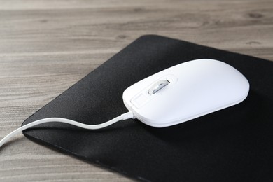 Wired mouse and mousepad on wooden table