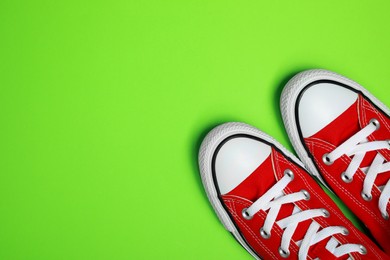 Photo of Pair of new stylish red sneakers on light green background, flat lay. Space for text