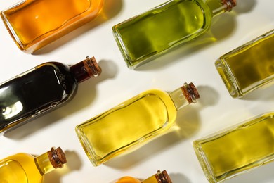 Photo of Vegetable fats. Different cooking oils in glass bottles on white background, flat lay