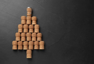 Photo of Christmas tree made of sparkling wine corks on black background, flat lay. Space for text