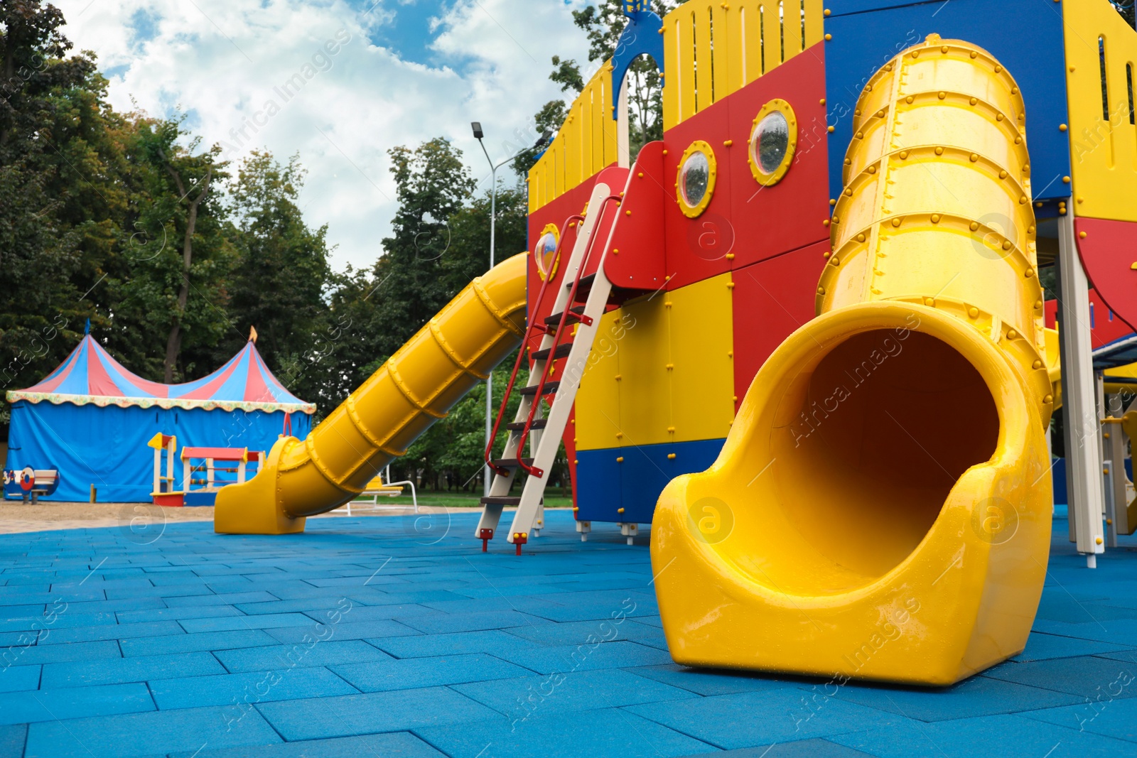 Photo of Children's playground with bright yellow slide on autumn day