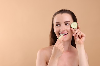 Photo of Beautiful woman with pieces of cucumber on beige background, space for text