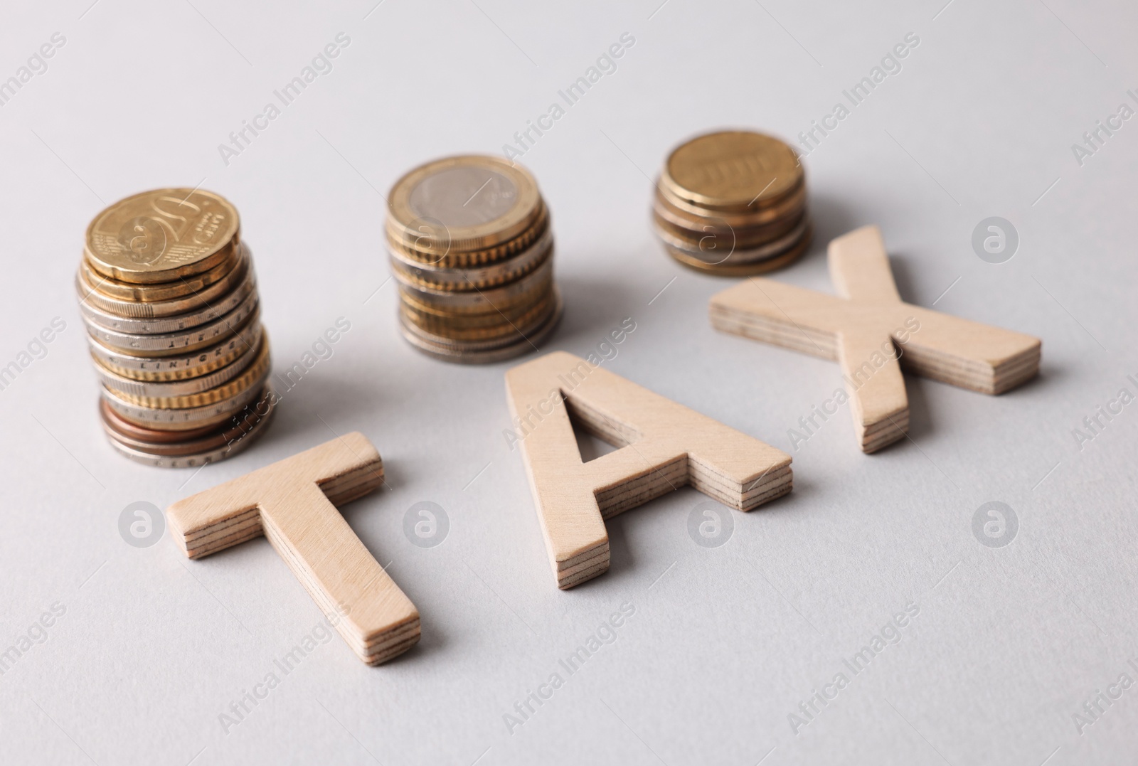 Photo of Word Tax made of wooden letters and coins on white background
