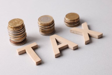 Word Tax made of wooden letters and coins on white background