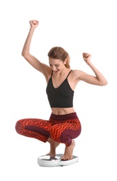 Photo of Happy young woman measuring her weight using scales on white background. Weight loss motivation