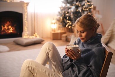 Photo of Young woman with cup of hot drink at home, space for text. Christmas celebration