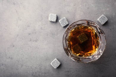 Golden whiskey in glass with cooling stones on table, top view. Space for text