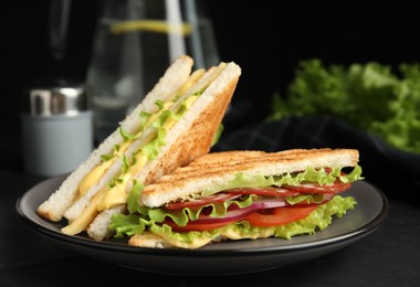 Plate with tasty sandwiches on black table