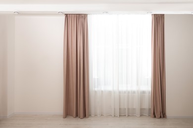 Photo of Elegant window curtains and white tulle indoors. Interior design