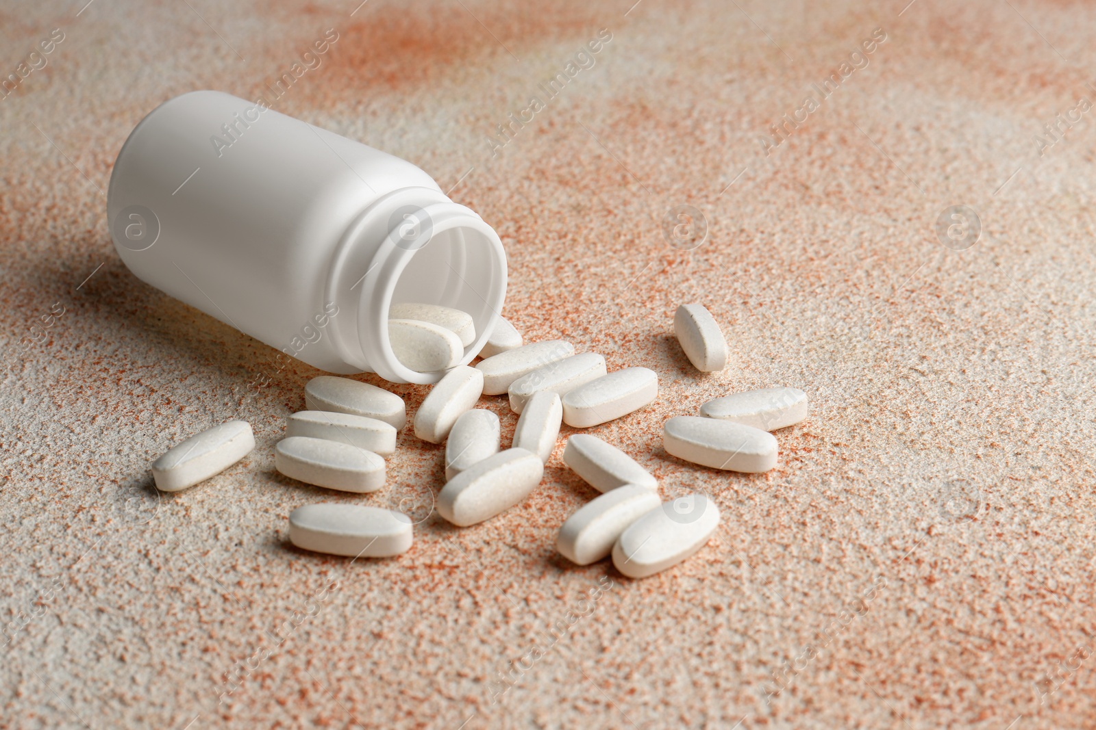 Photo of White medical bottle and pills on color textured surface, space for text